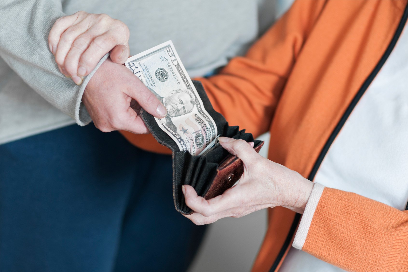 Woman takes money from the purse of an older woman (Getty Images/uba-foto)