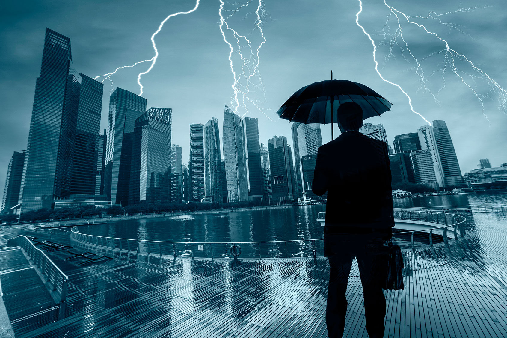Businessman With Umbrella Looking Storm Over City (Getty Images/guvendemir)