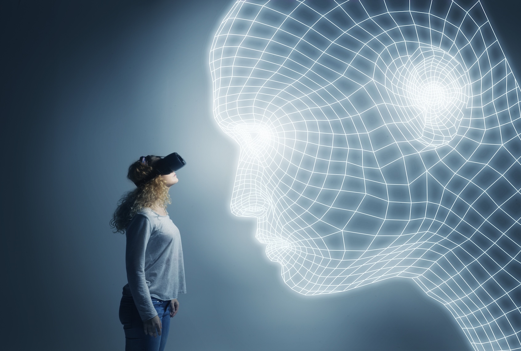 Young woman next to lighttrace face, wearing VR glasses, looking closely at the lightrace rendering. (Getty Images / Henrik Sorensen)