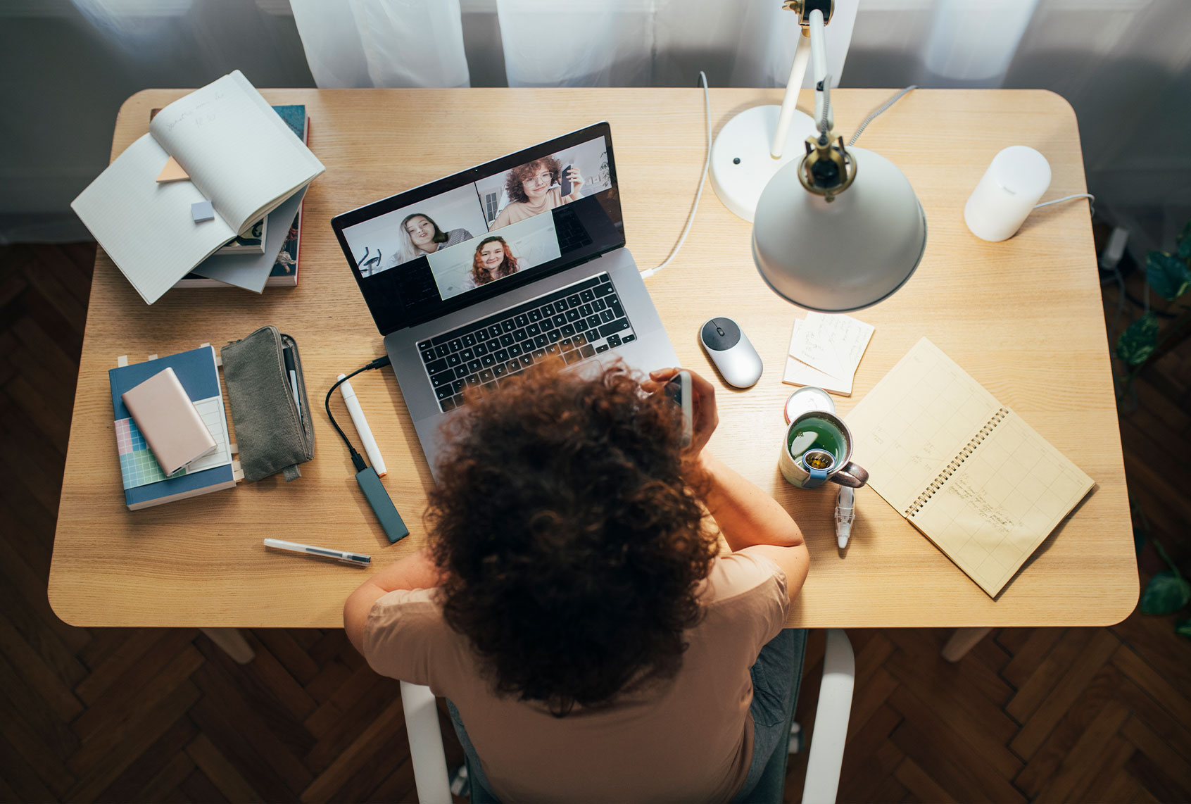 A woman sitting at her desk talking to her colleagues in a meeting using her laptop computer (Getty Images/FreshSplash)