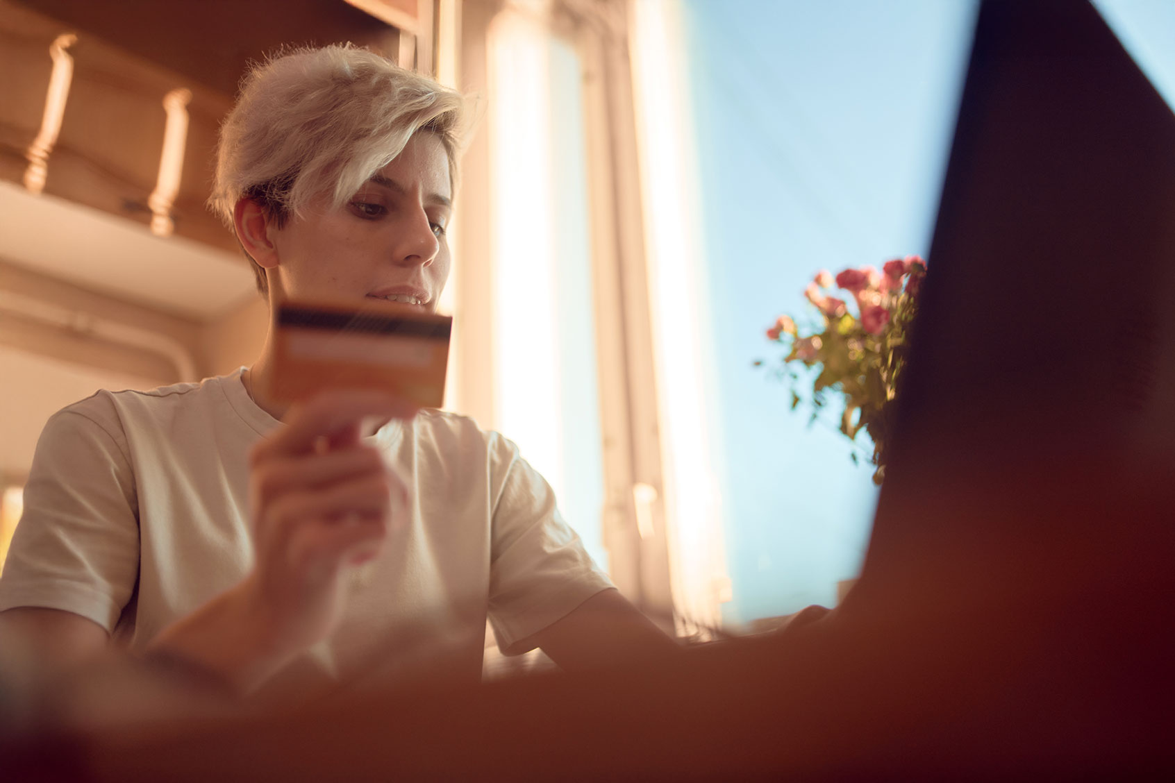Woman holding credit card and typing on laptop at home. (Getty Images/Sergey Mironov)